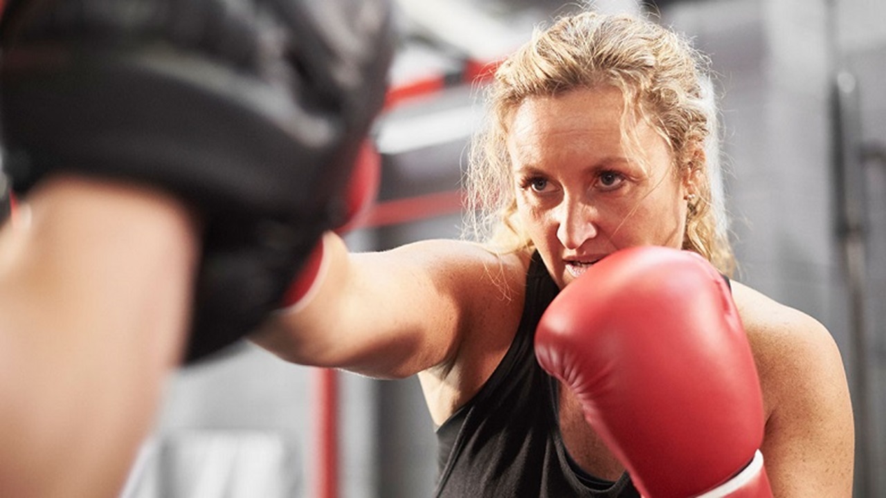 Female boxer with red gloves punching pads