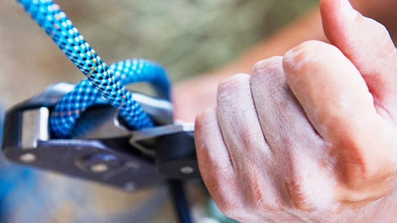Closeup of a hand securing a climbing clip